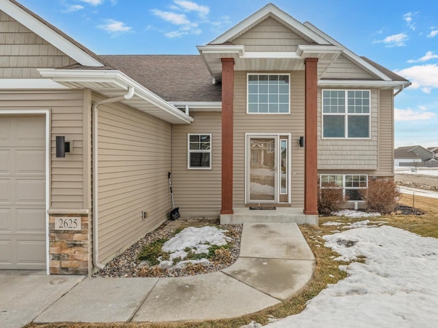 property entrance featuring roof with shingles and an attached garage