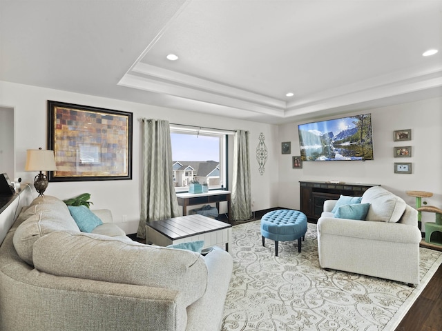 living room featuring recessed lighting, a raised ceiling, baseboards, and wood finished floors