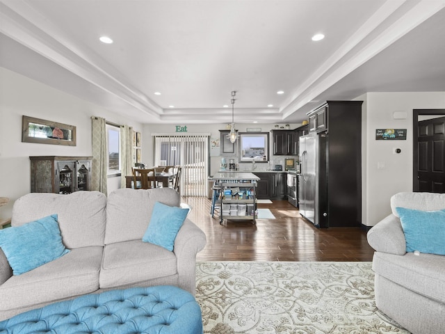 living room featuring a tray ceiling, dark wood-type flooring, and recessed lighting