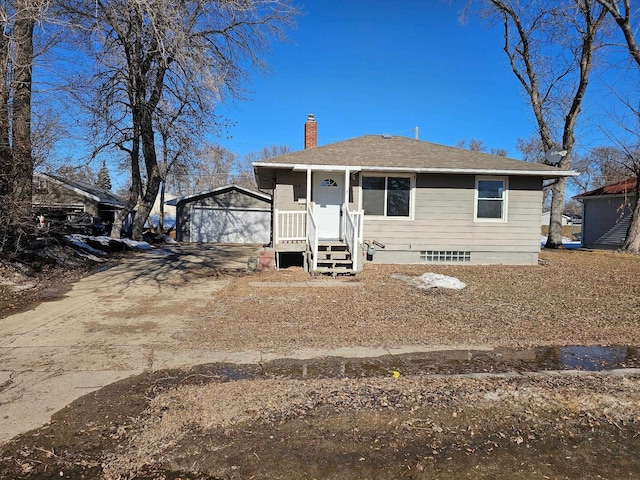 view of front of property featuring a garage, an outbuilding, roof with shingles, and a chimney