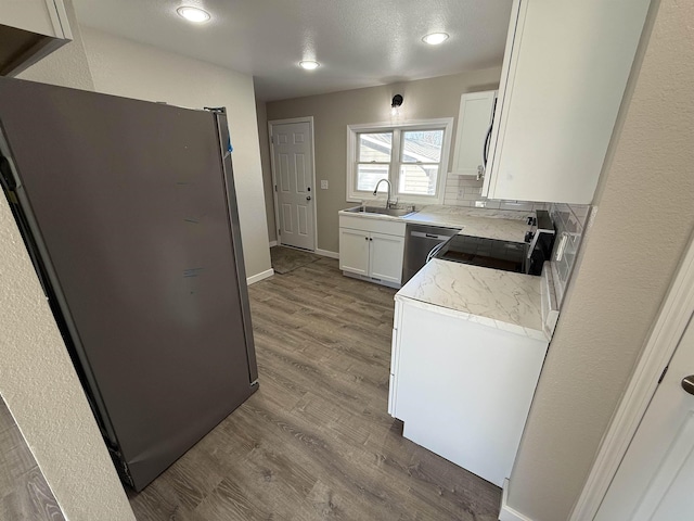 kitchen with decorative backsplash, dark wood finished floors, stainless steel appliances, white cabinetry, and a sink