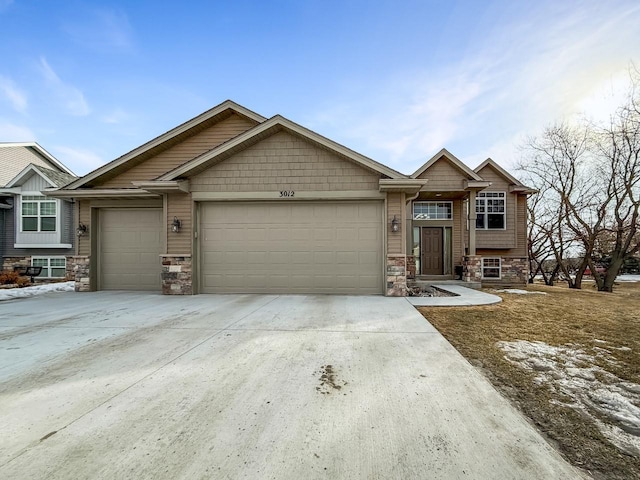 view of front of house featuring stone siding, an attached garage, and driveway