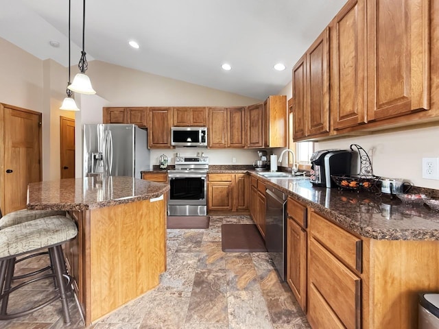 kitchen featuring stainless steel appliances, a breakfast bar, a kitchen island, a sink, and brown cabinets