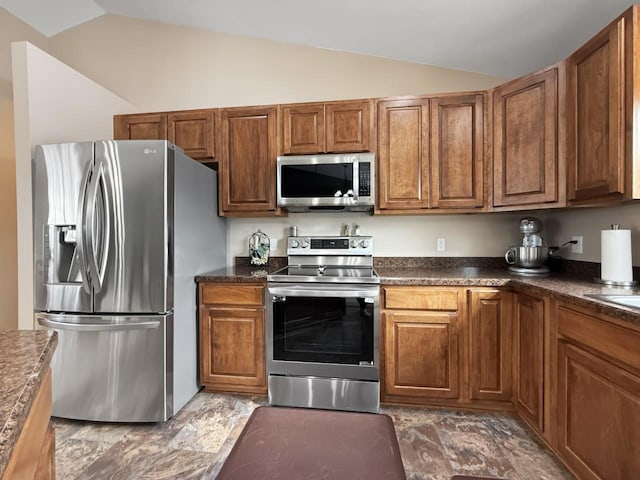 kitchen featuring dark countertops, appliances with stainless steel finishes, and vaulted ceiling