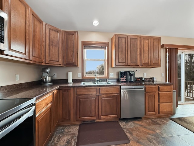 kitchen featuring dark countertops, brown cabinets, stainless steel appliances, and a sink