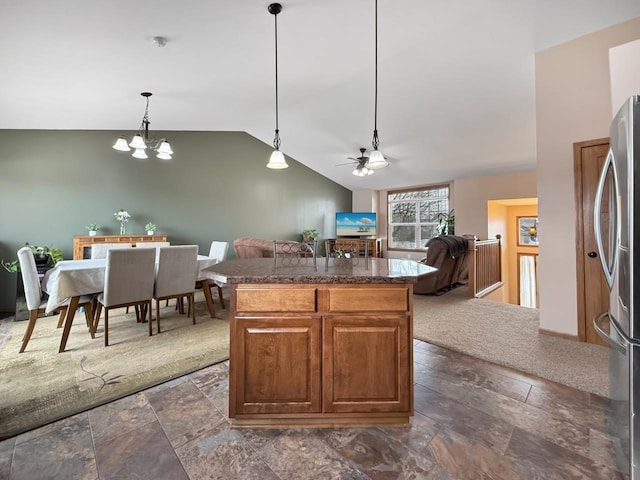 kitchen with lofted ceiling, open floor plan, hanging light fixtures, freestanding refrigerator, and a center island