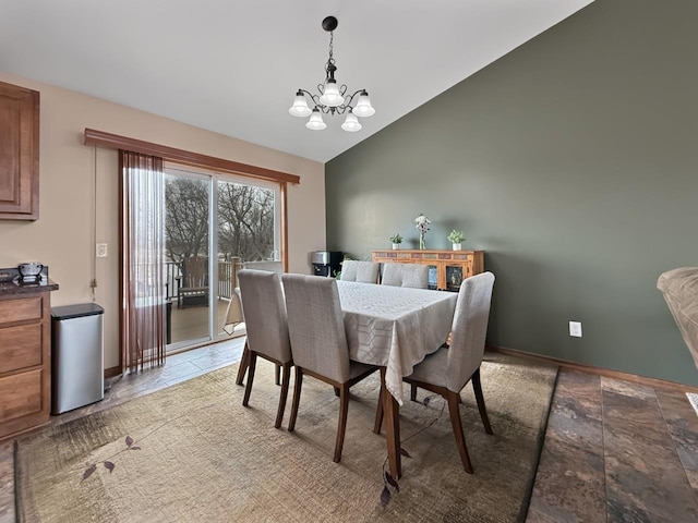 dining room featuring vaulted ceiling, stone finish flooring, baseboards, and a notable chandelier