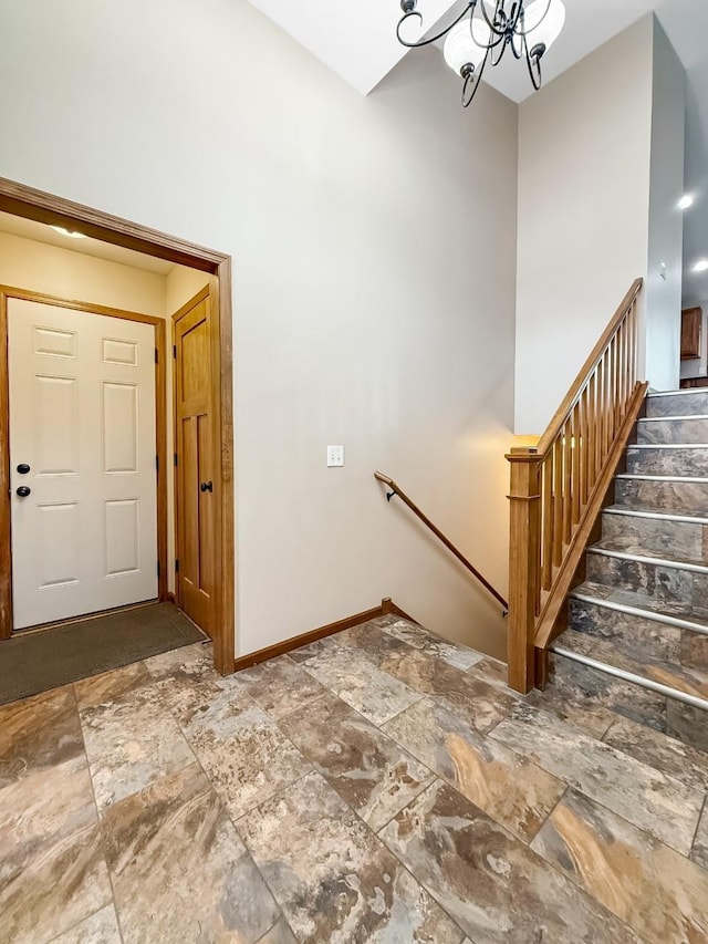 staircase featuring a chandelier, stone finish floor, and baseboards