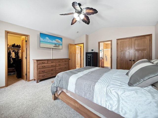 bedroom with lofted ceiling, ceiling fan, connected bathroom, a closet, and carpet