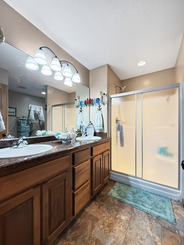 full bath with a stall shower, a sink, and double vanity