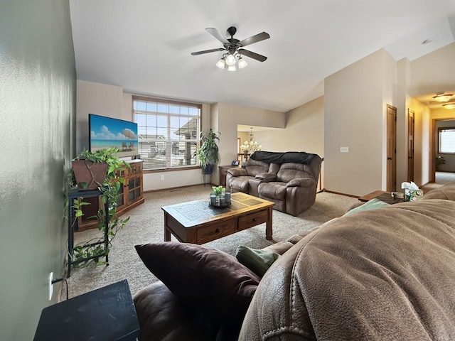 carpeted living room featuring baseboards and ceiling fan with notable chandelier