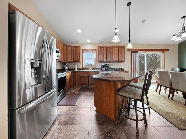 kitchen with a center island, brown cabinets, stainless steel appliances, a healthy amount of sunlight, and a sink