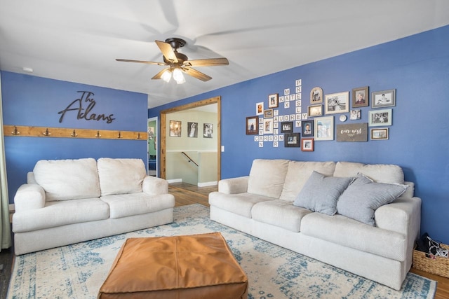 living area featuring wood finished floors, a ceiling fan, and baseboards