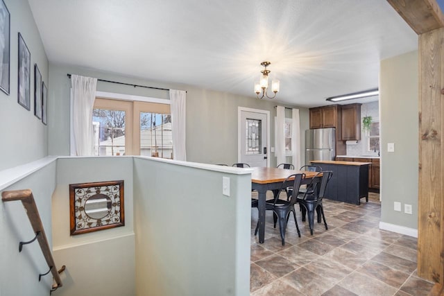 interior space featuring light countertops, hanging light fixtures, freestanding refrigerator, a chandelier, and baseboards