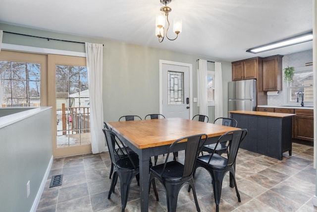 dining space featuring an inviting chandelier, stone finish flooring, visible vents, and baseboards