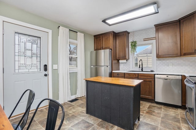 kitchen with stainless steel appliances, tasteful backsplash, a wealth of natural light, wooden counters, and a sink