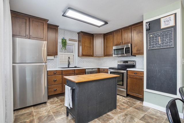 kitchen featuring appliances with stainless steel finishes, butcher block counters, a sink, and tasteful backsplash