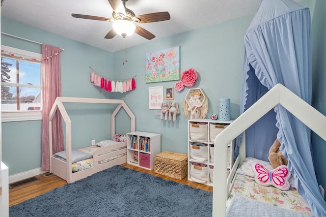 bedroom featuring ceiling fan, wood finished floors, visible vents, and baseboards