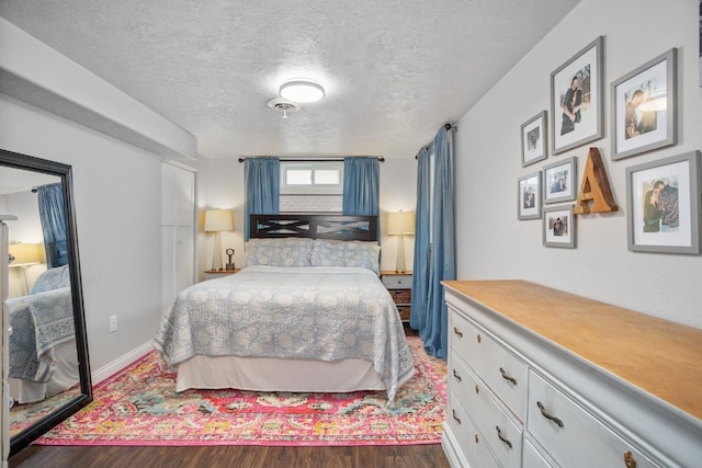 bedroom featuring a textured ceiling, baseboards, and dark wood-type flooring