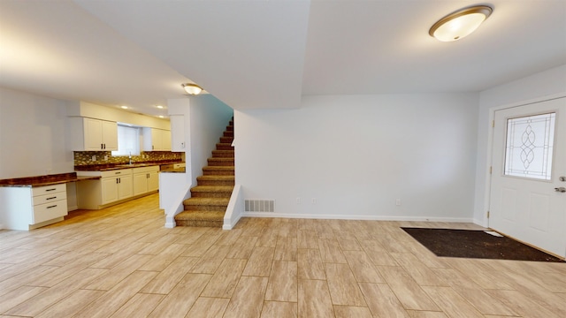 entryway featuring stairway, light wood-type flooring, visible vents, and baseboards