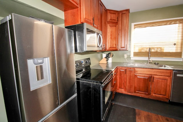 kitchen with dark wood-style floors, appliances with stainless steel finishes, brown cabinets, and a sink