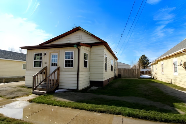 view of front of property featuring entry steps, fence, and a front lawn