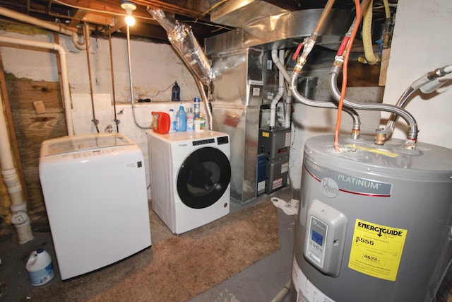 clothes washing area featuring heating unit, laundry area, water heater, and separate washer and dryer