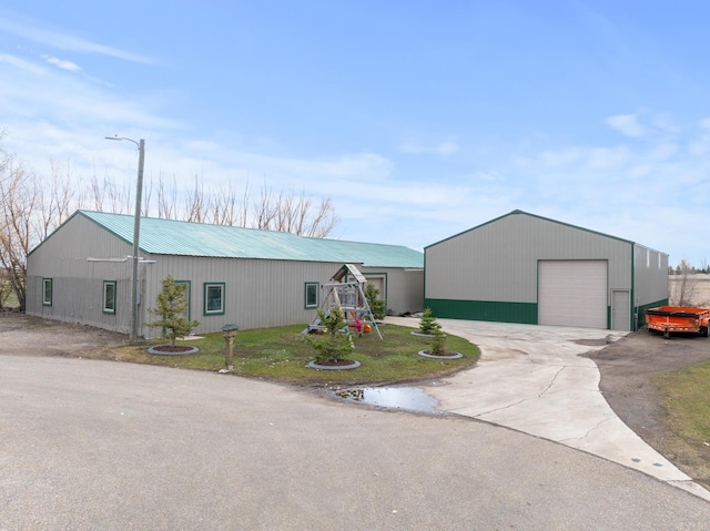 view of front facade with a detached garage, metal roof, an outbuilding, and an outdoor structure