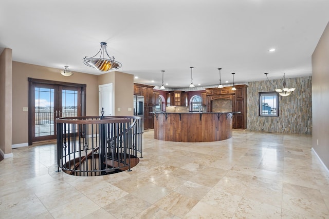 kitchen with decorative light fixtures, french doors, a center island with sink, and a kitchen breakfast bar