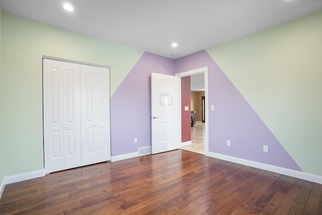 unfurnished bedroom with recessed lighting, a closet, visible vents, baseboards, and hardwood / wood-style flooring