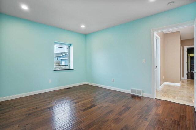 empty room featuring hardwood / wood-style flooring, recessed lighting, visible vents, and baseboards