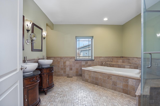 bathroom with a garden tub, vanity, tile walls, wainscoting, and a stall shower