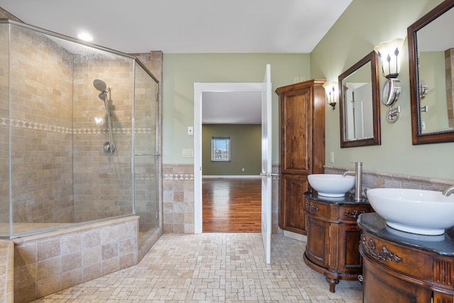 full bath with tiled shower, vanity, and tile walls