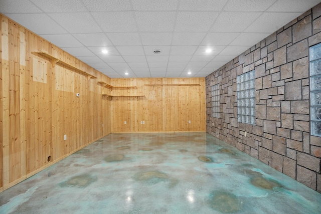 below grade area featuring wood walls and a paneled ceiling