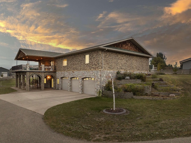 view of front of house featuring a front yard, concrete driveway, a balcony, and an attached garage