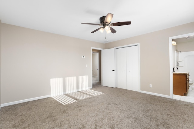 unfurnished bedroom featuring ceiling fan, connected bathroom, light carpet, baseboards, and a closet