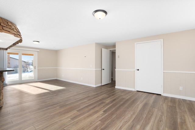 unfurnished living room with a wainscoted wall and wood finished floors