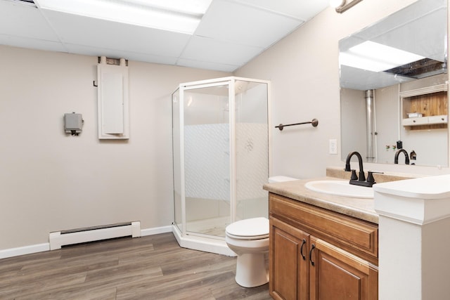 bathroom featuring a baseboard radiator, toilet, vanity, a shower stall, and wood finished floors