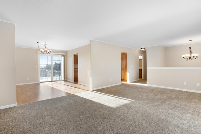 spare room with ornamental molding, a notable chandelier, and light colored carpet