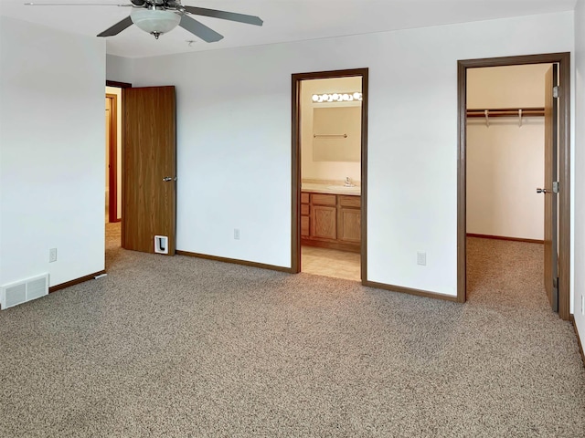 unfurnished bedroom with visible vents, baseboards, light colored carpet, and a spacious closet