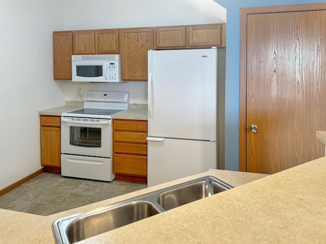 kitchen with brown cabinets, a sink, white appliances, light countertops, and baseboards