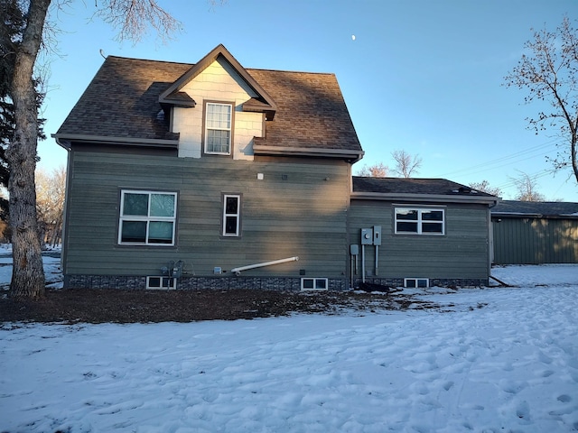 snow covered rear of property featuring roof with shingles