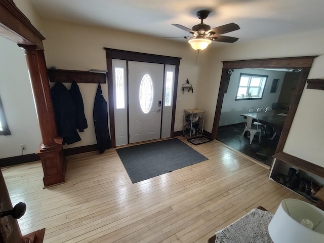 foyer featuring baseboards, light wood-type flooring, ornate columns, and ceiling fan