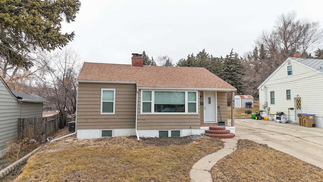 bungalow-style home featuring roof with shingles, central AC unit, a chimney, and fence