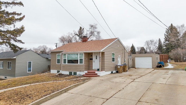 bungalow-style house featuring an outbuilding, concrete driveway, a shingled roof, a garage, and a chimney