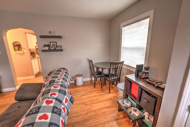 living room featuring light wood-style flooring, baseboards, and arched walkways