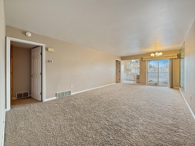 carpeted spare room with a chandelier, visible vents, and baseboards