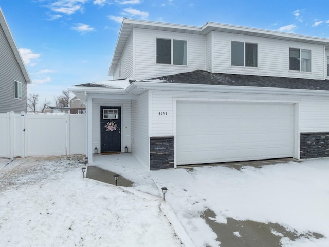 view of front of property with a garage, stone siding, fence, and a gate