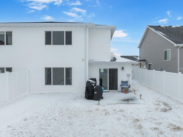 snow covered house featuring a fenced backyard