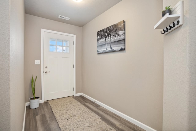 doorway to outside featuring visible vents, baseboards, and wood finished floors